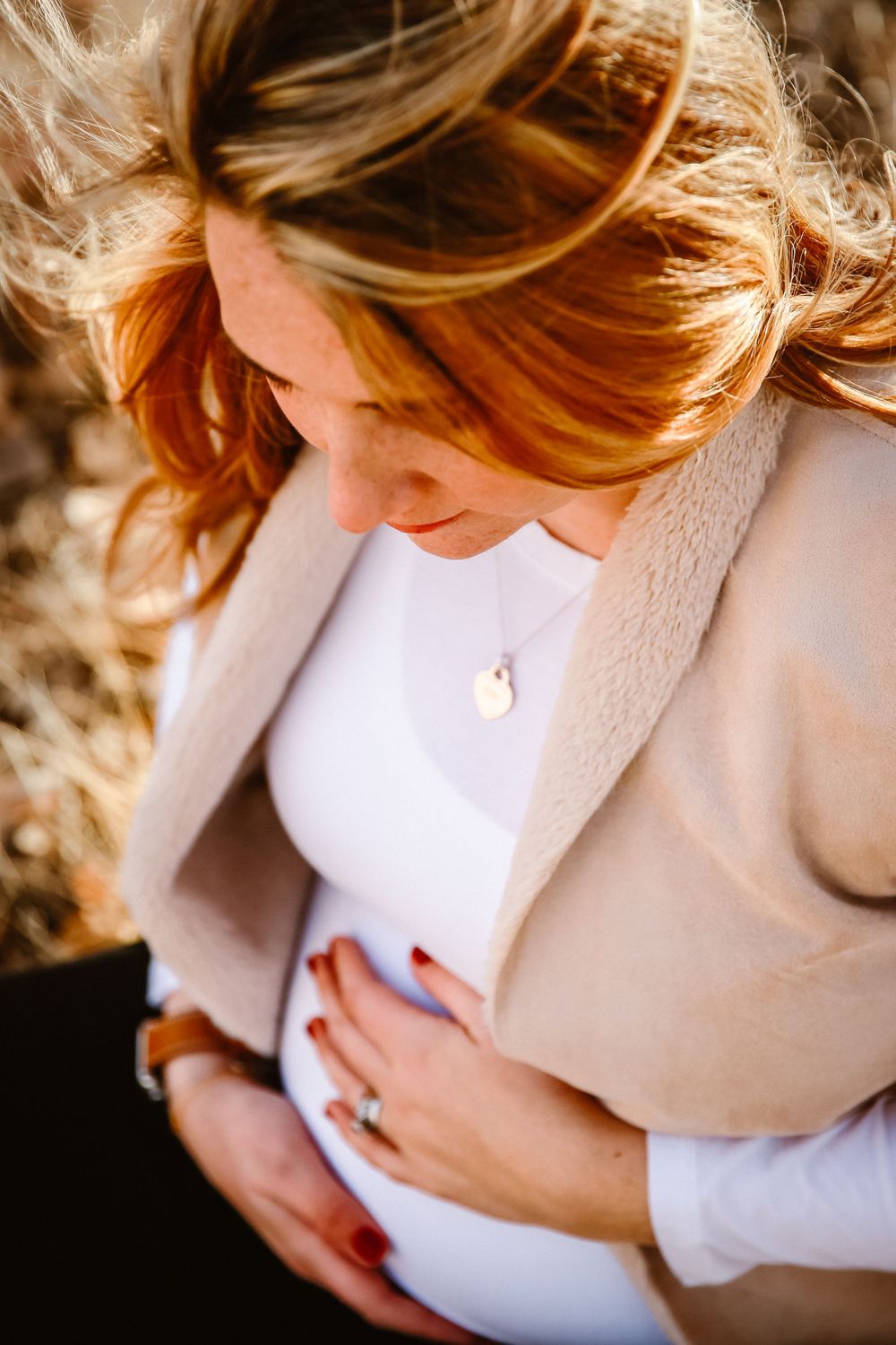 A pregnant mother cradles her baby bump as her hair blows in the wind
