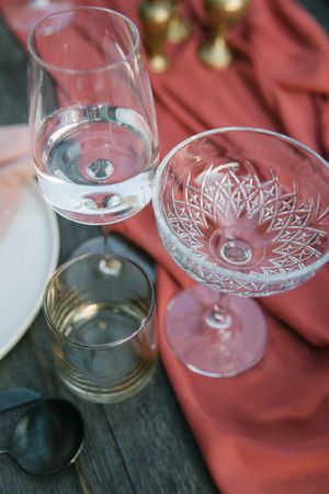 Water and champagne glasses on a table with coral coloured linen.