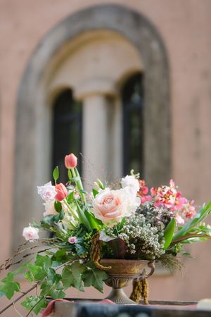 A floral arrangement with Italian style windows showing in teh background.