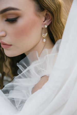 Ruffled tulle shows off the delicate Miinella earrings and necklaces on a woman.