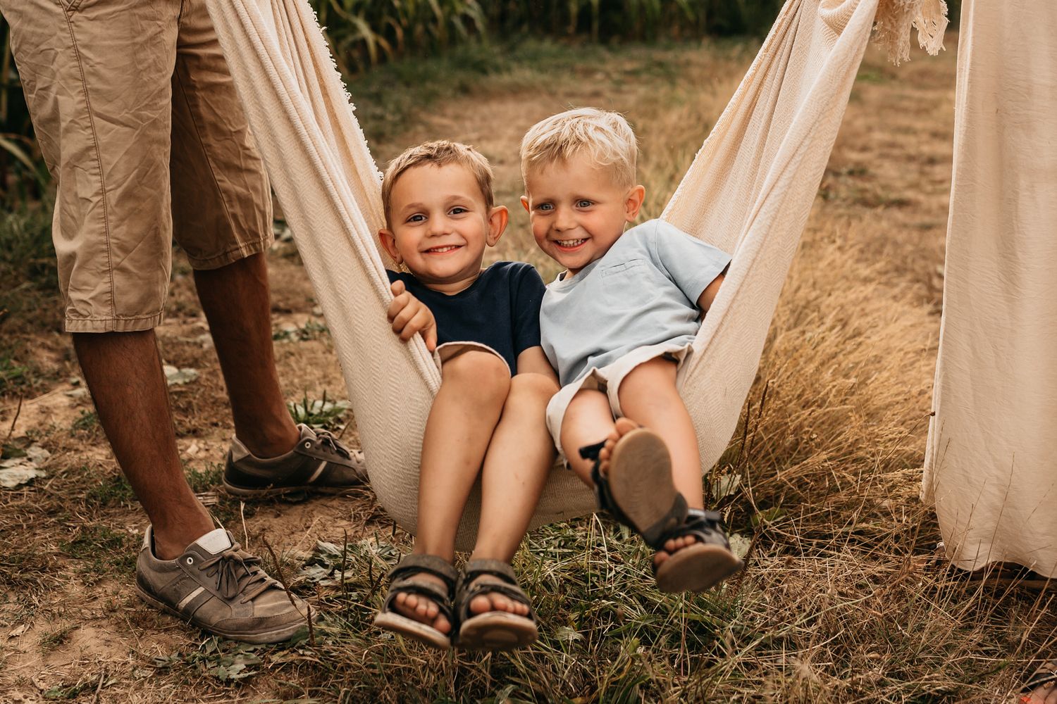 Children relax together in a hammock during a sunny outdoor gathering.