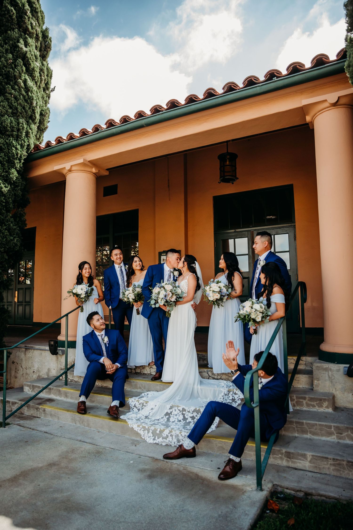 All blue bridal party watches newlyweds kiss after Point Loma wedding at Liberty Station in San Diego