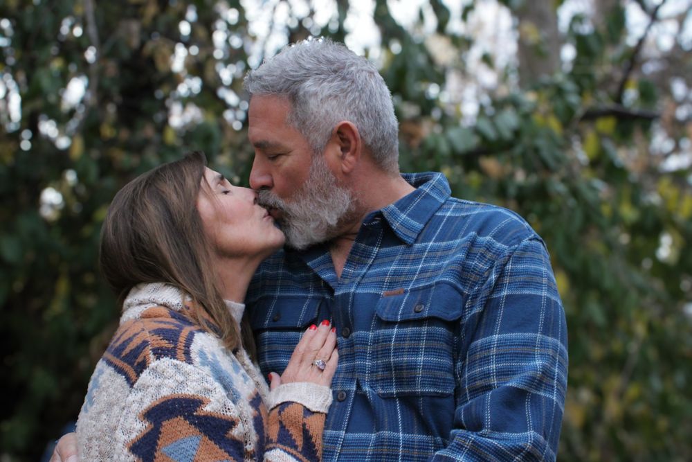A romantic outdoor moment between a couple wearing blue plaid and patterned sweaters.