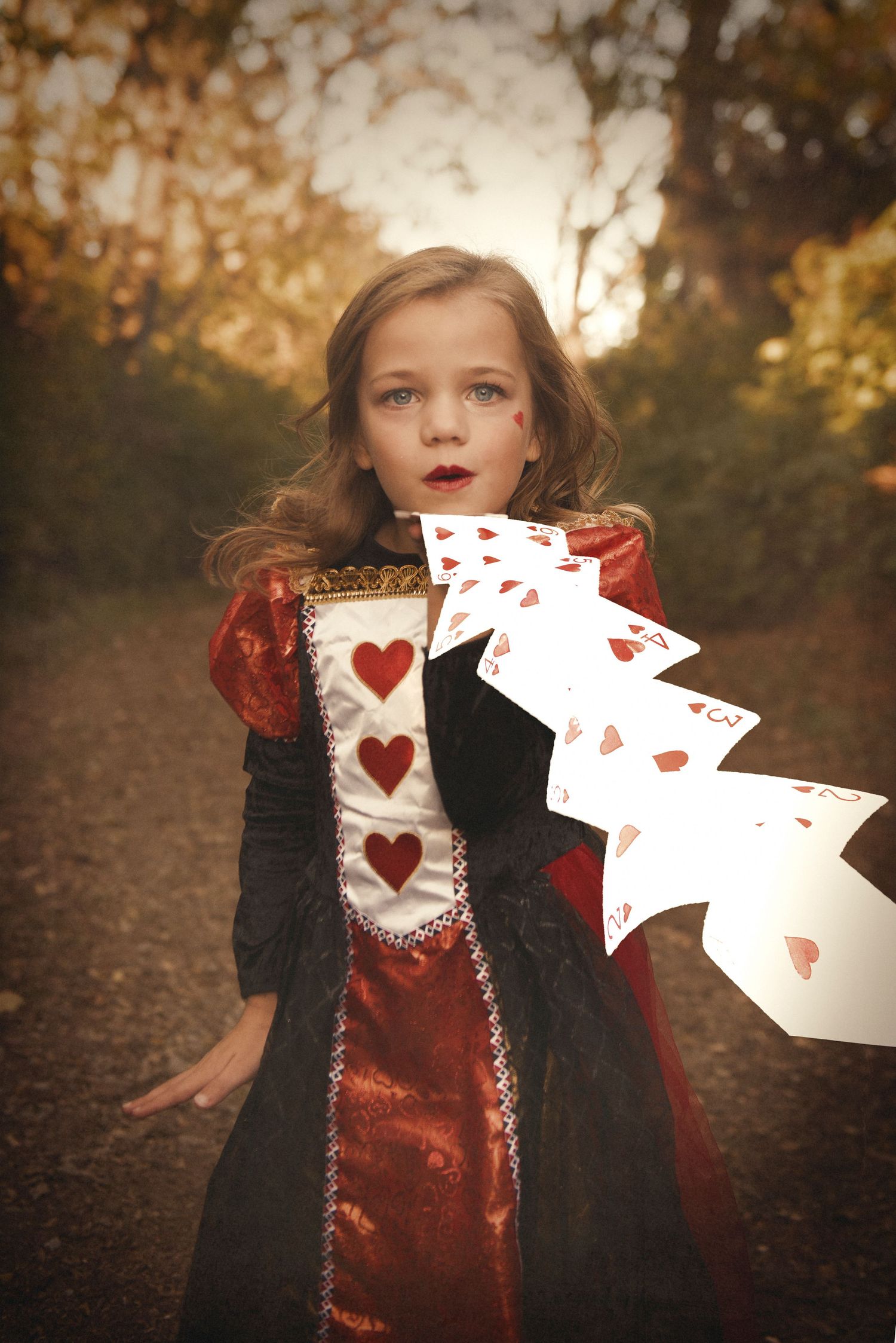 Creative portrait featuring playing cards with heart designs against a dark background.