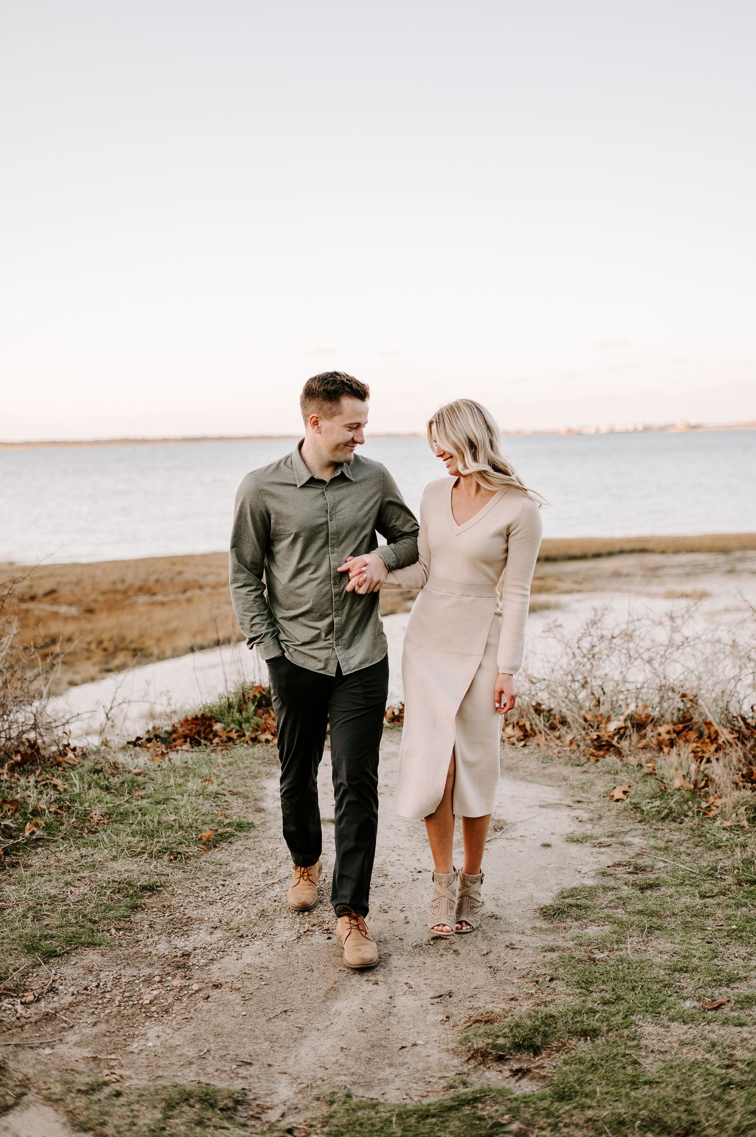 Couple walking together on coastal path during golden hour photoshoot.