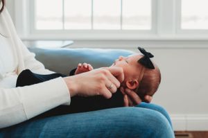 Mom gently touching her newborn baby's cheek - lifestyle photographer in South Heart, ND