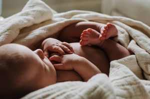Newborn baby wrapped gently in neutral tones - natural light photographer in Dickinson, ND