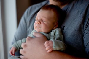 Baby snuggled up with Dad during a lifestyle session - newborn photography in Dickinson, ND