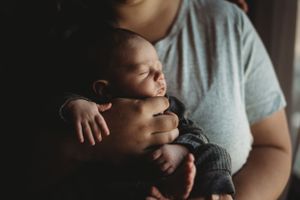 Mom holding baby in home during lifestyle newborn photography session in Dickinson, ND