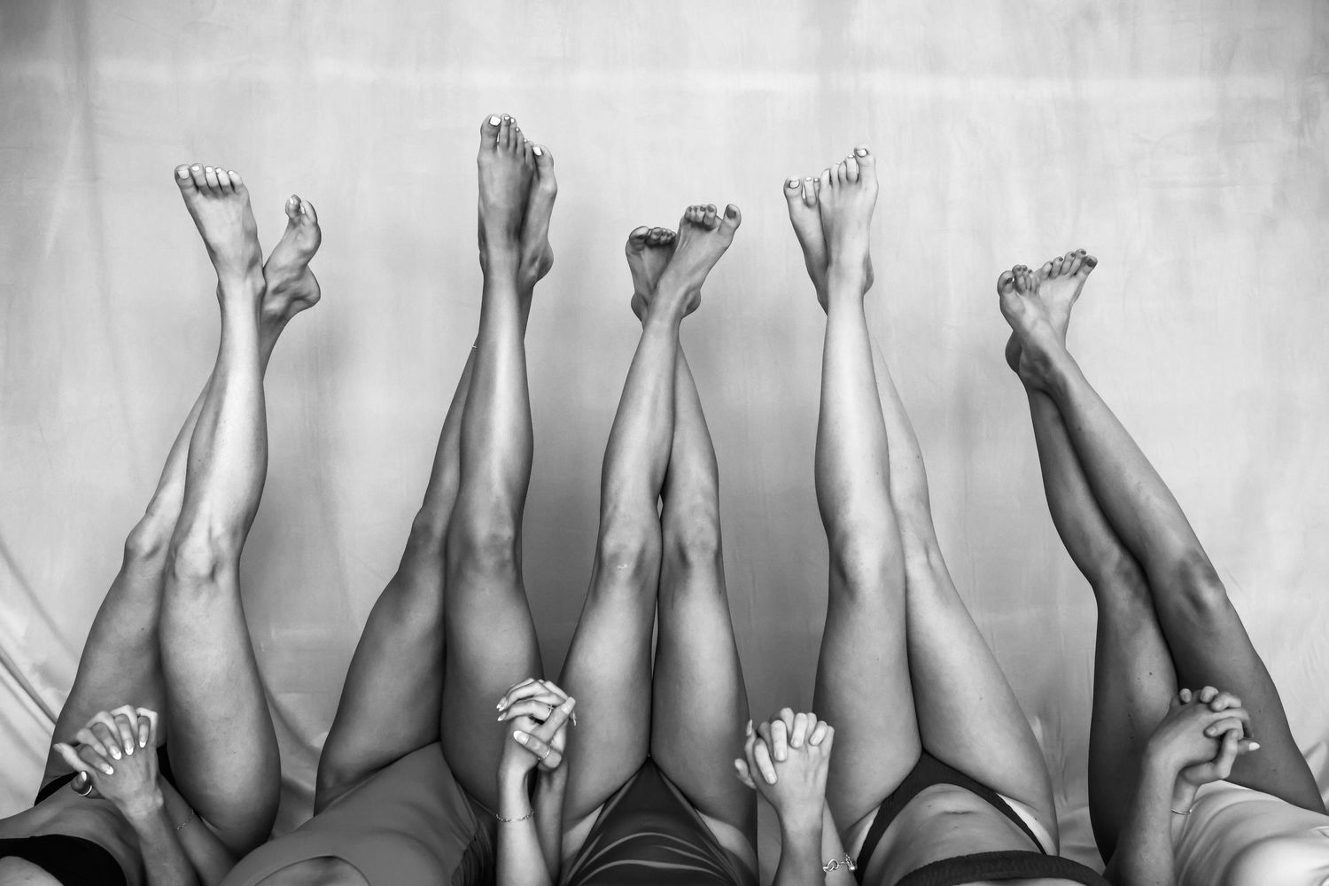Black and white artistic photograph showing raised feet and legs against a white background.