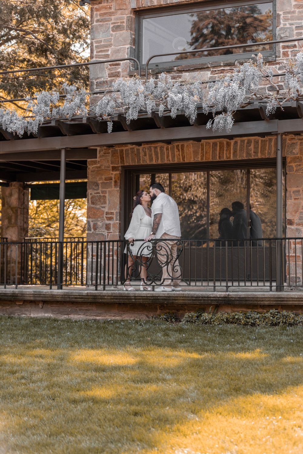 Romantic couple shares a tender moment on a rustic balcony at sunset.