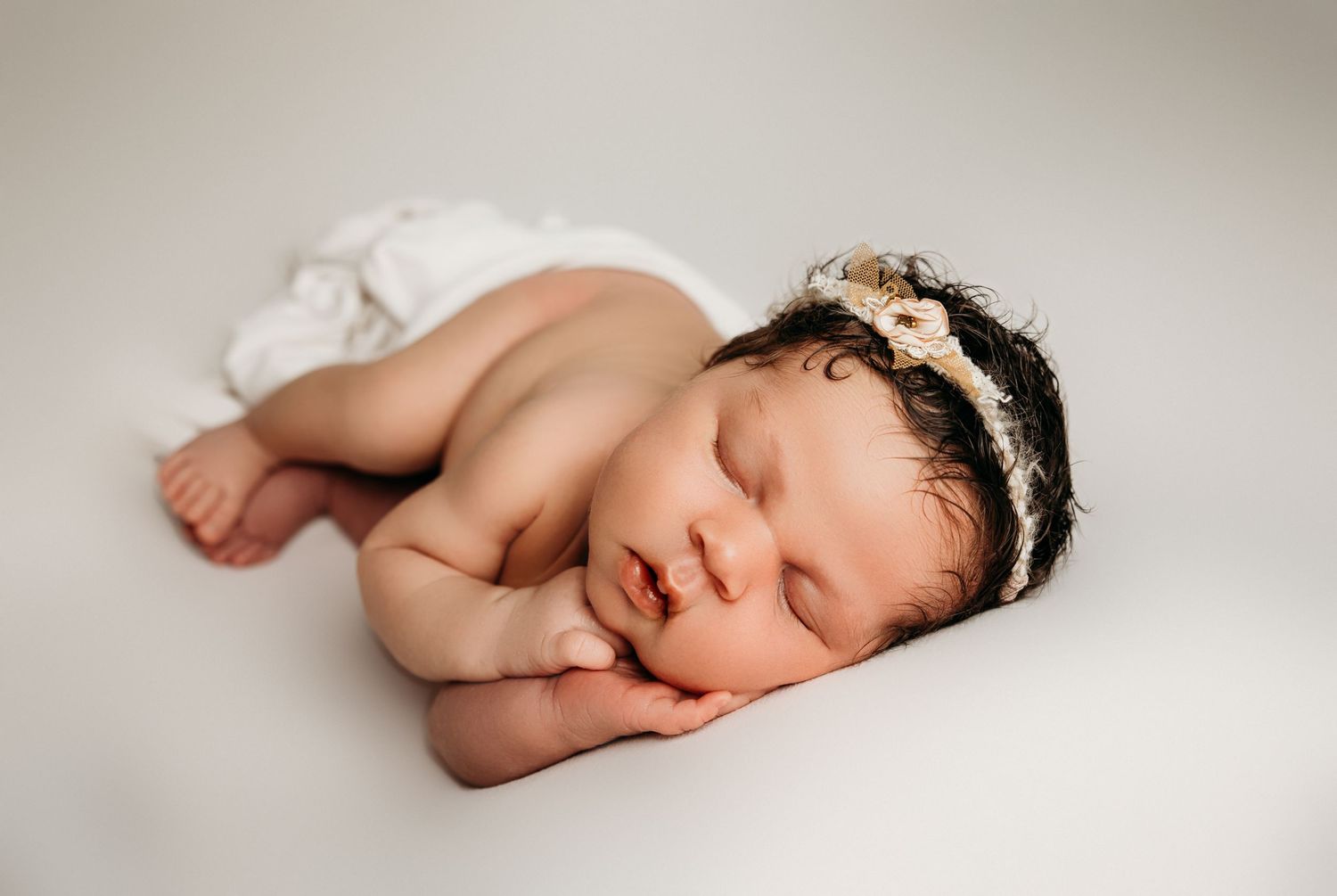 Peaceful newborn photography series on white backdrop showing sleeping baby.
