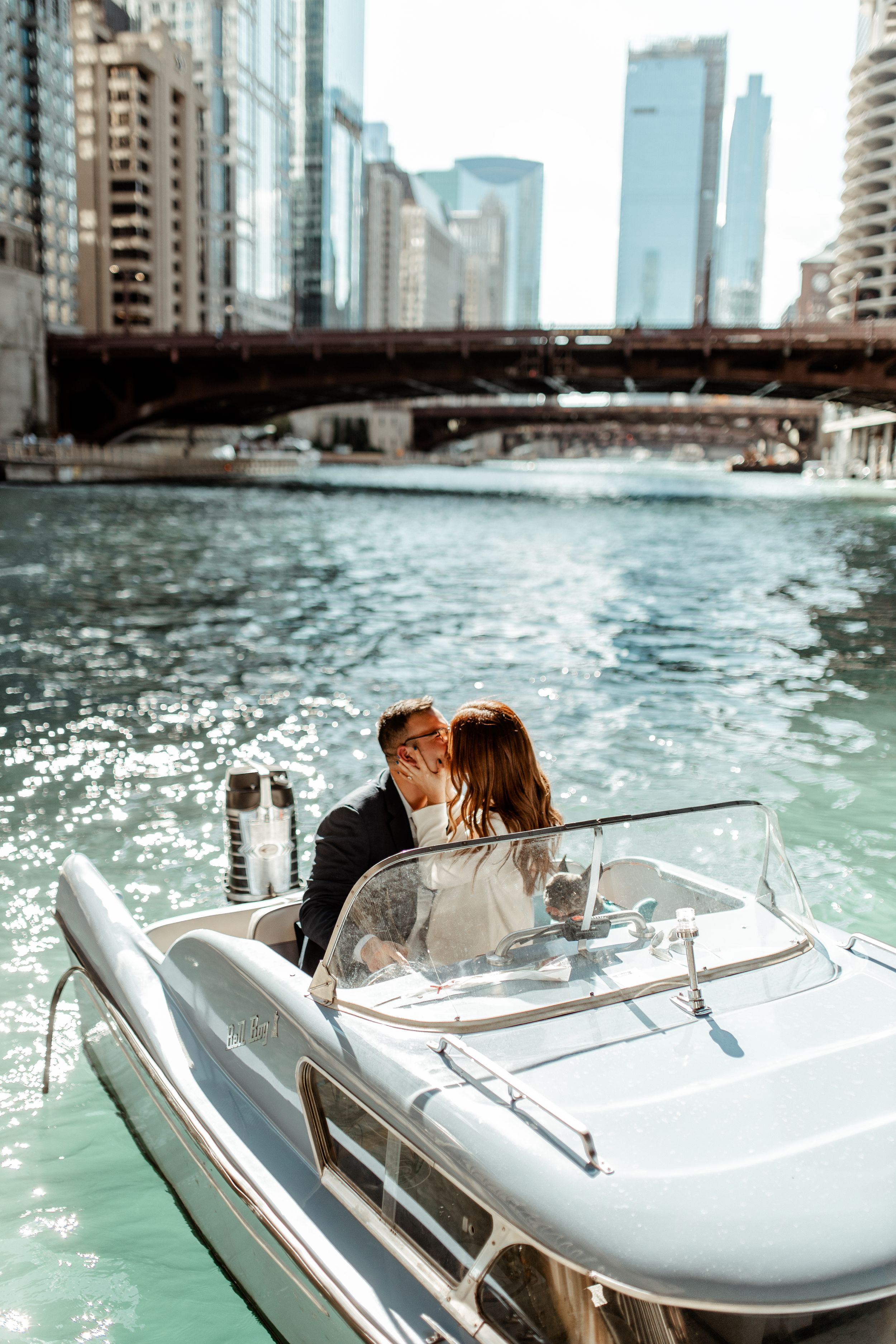 Couple enjoying romantic boat ride on Chicago River with city skyline in background.