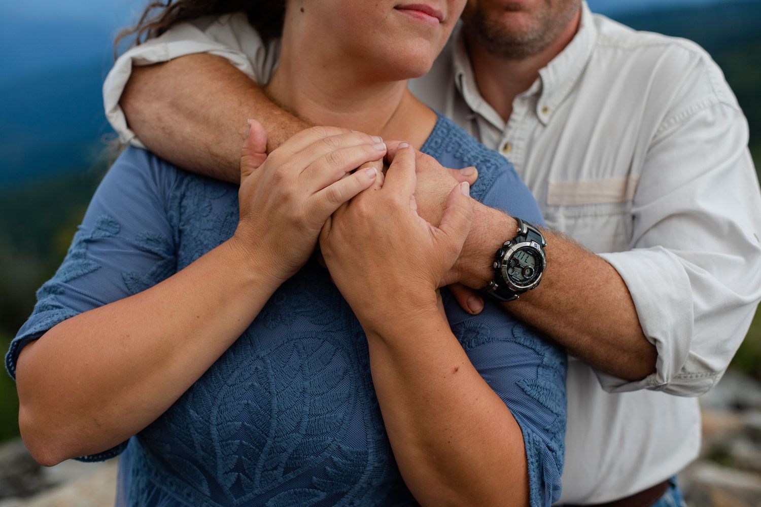 Close-up shots of couple embracing against blue mountain vista backdrop.