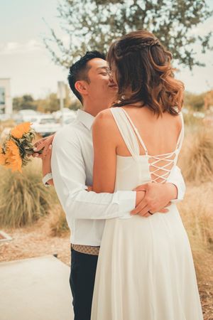 A tender embrace between newlyweds with sunflowers and desert landscape in the background.