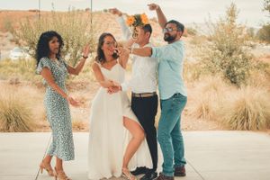 A joyful outdoor celebration with friends wearing stylish outfits and dancing in a desert setting.