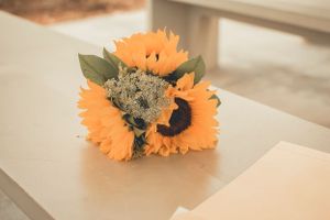 Beautiful arrangement of bright orange sunflowers and greenery on a white surface.