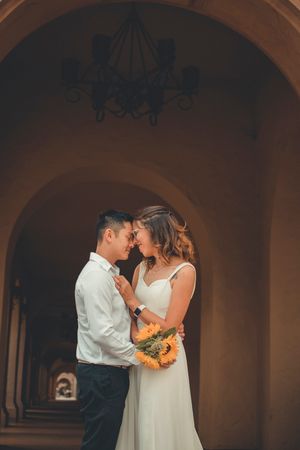 Intimate moment captured in an architectural colonnade with warm lighting and sunflower bouquet.