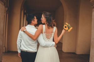 Couple walking through arched hallway with sunflowers and white dress.