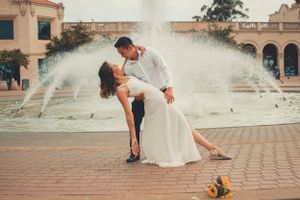 Romantic dip pose in front of fountain with sunflowers on brick plaza.