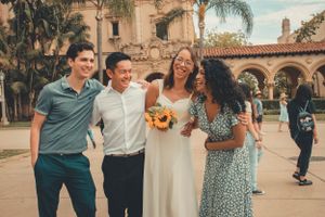 Group celebrating at wedding with sunflowers by Spanish-style architecture.