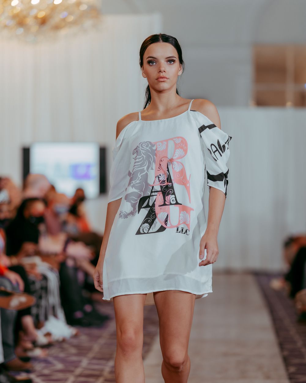 Casual white t-shirt look presented on runway with graphic art detail.