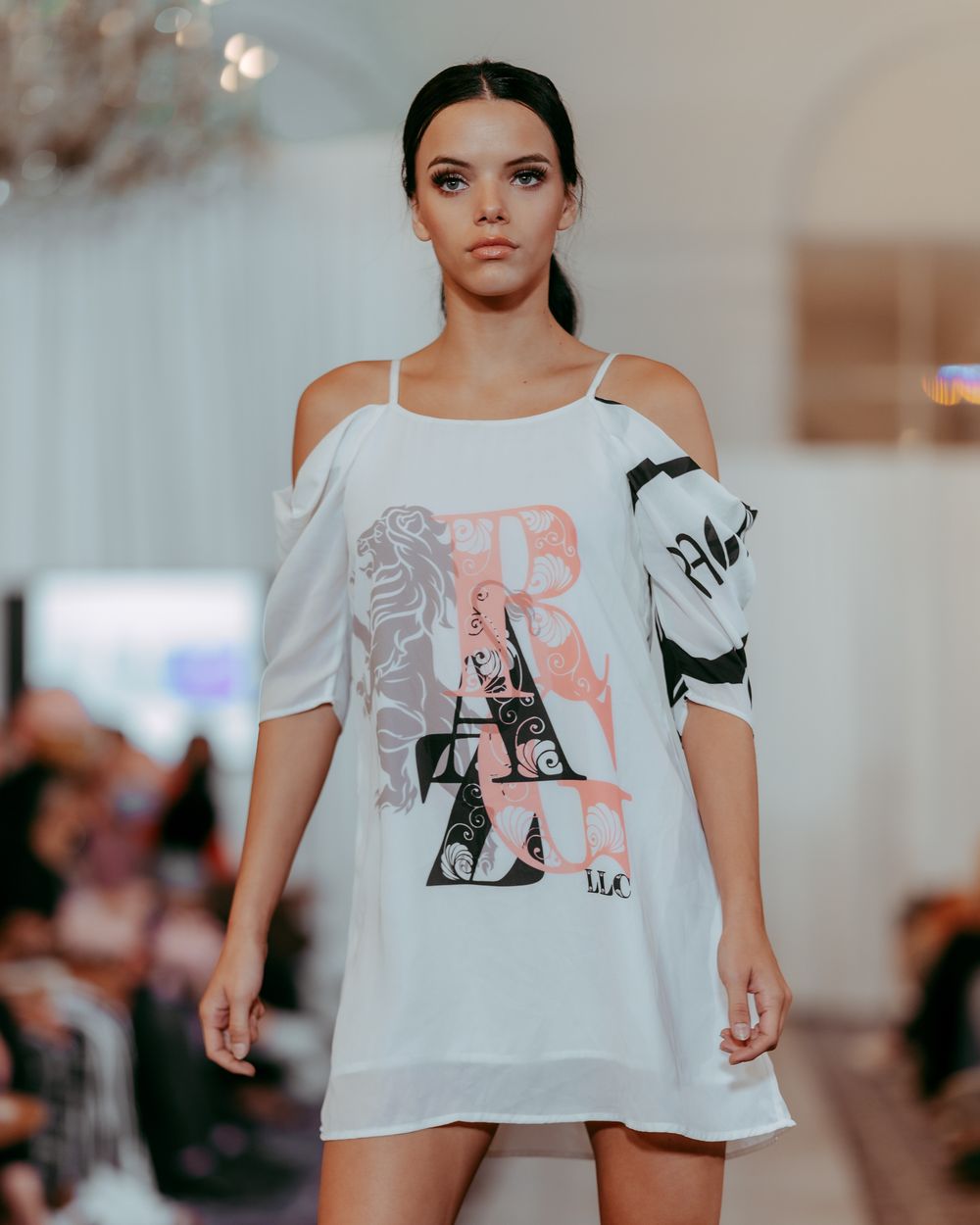Runway presentation of oversized white graphic tee paired with white boots.
