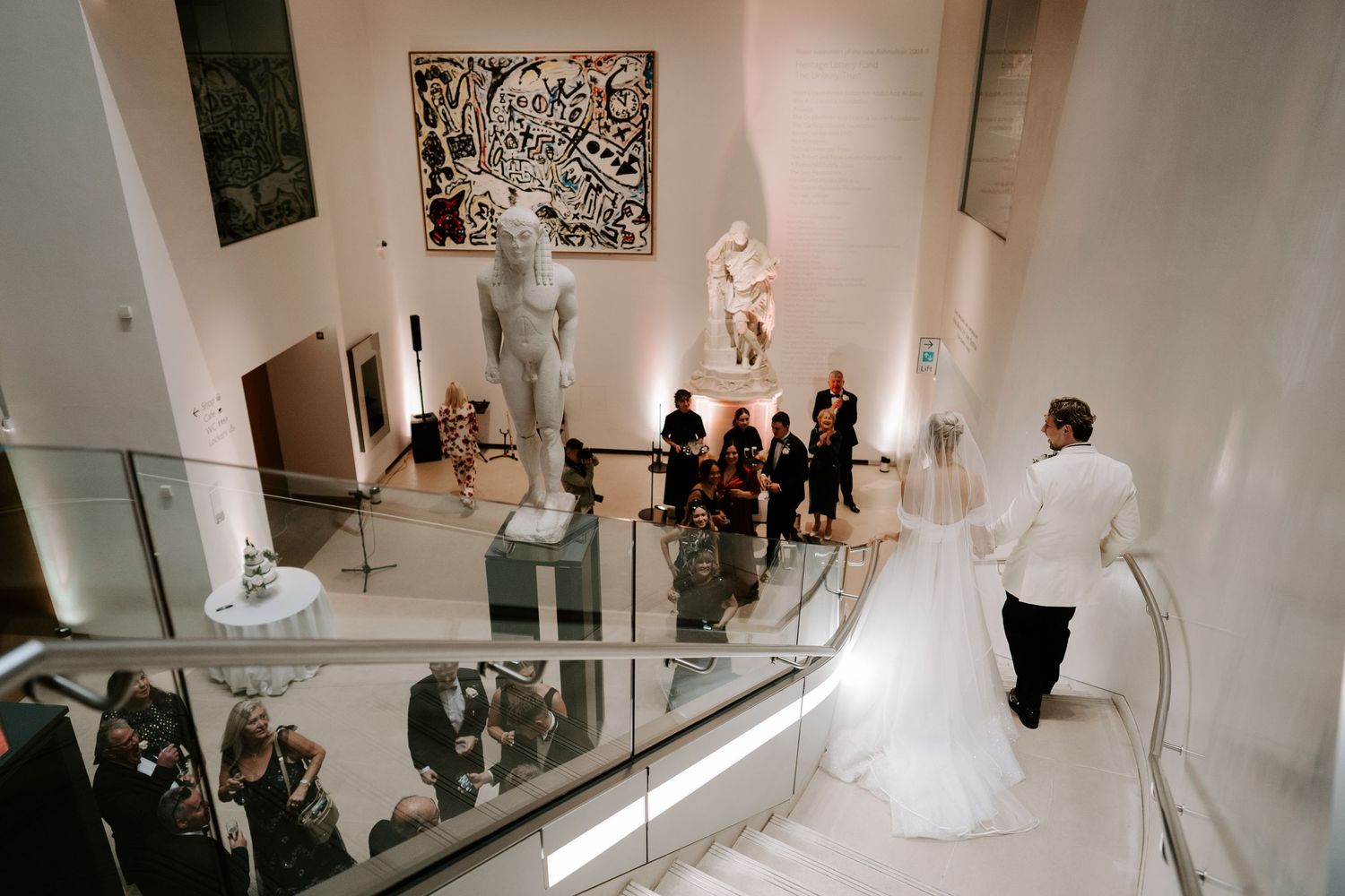 bride and groom descending stairs in the atrium at the ashmolean museum in Oxford