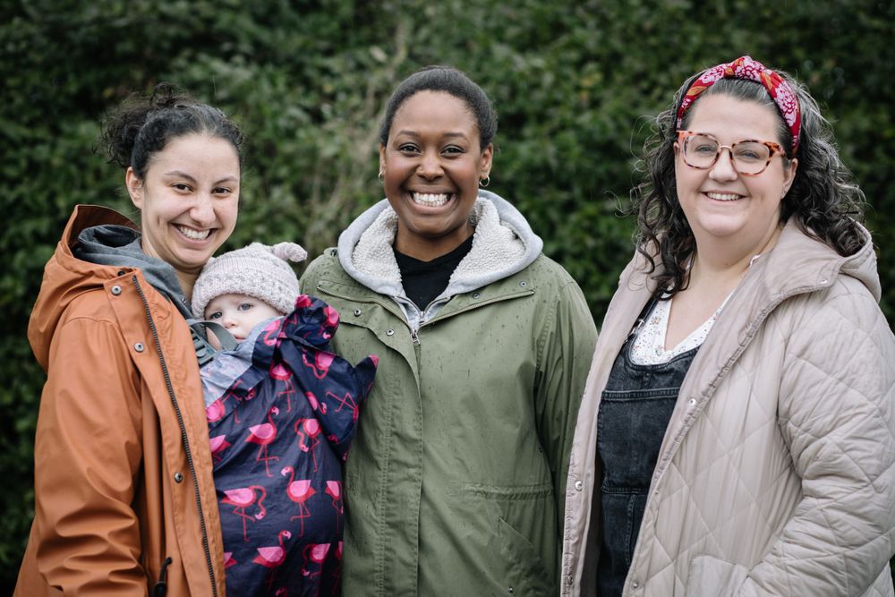 Group of friends in warm outerwear pose together outdoors on an overcast day.
