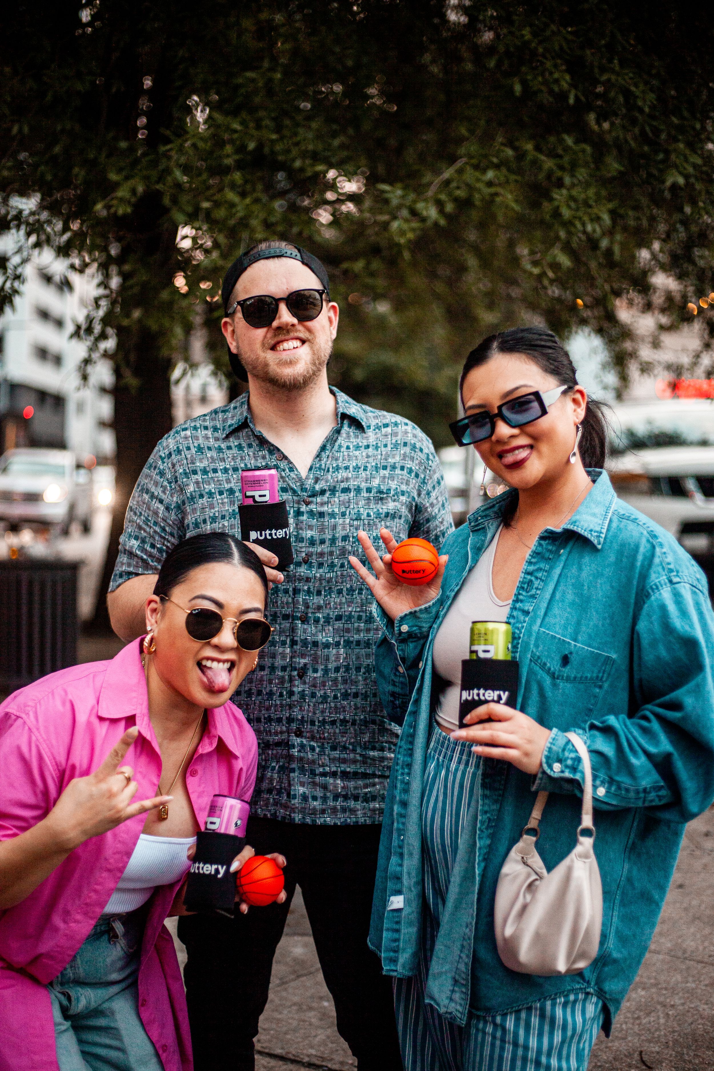 Friends in casual attire enjoying colorful drinks together outdoors on sunny day.