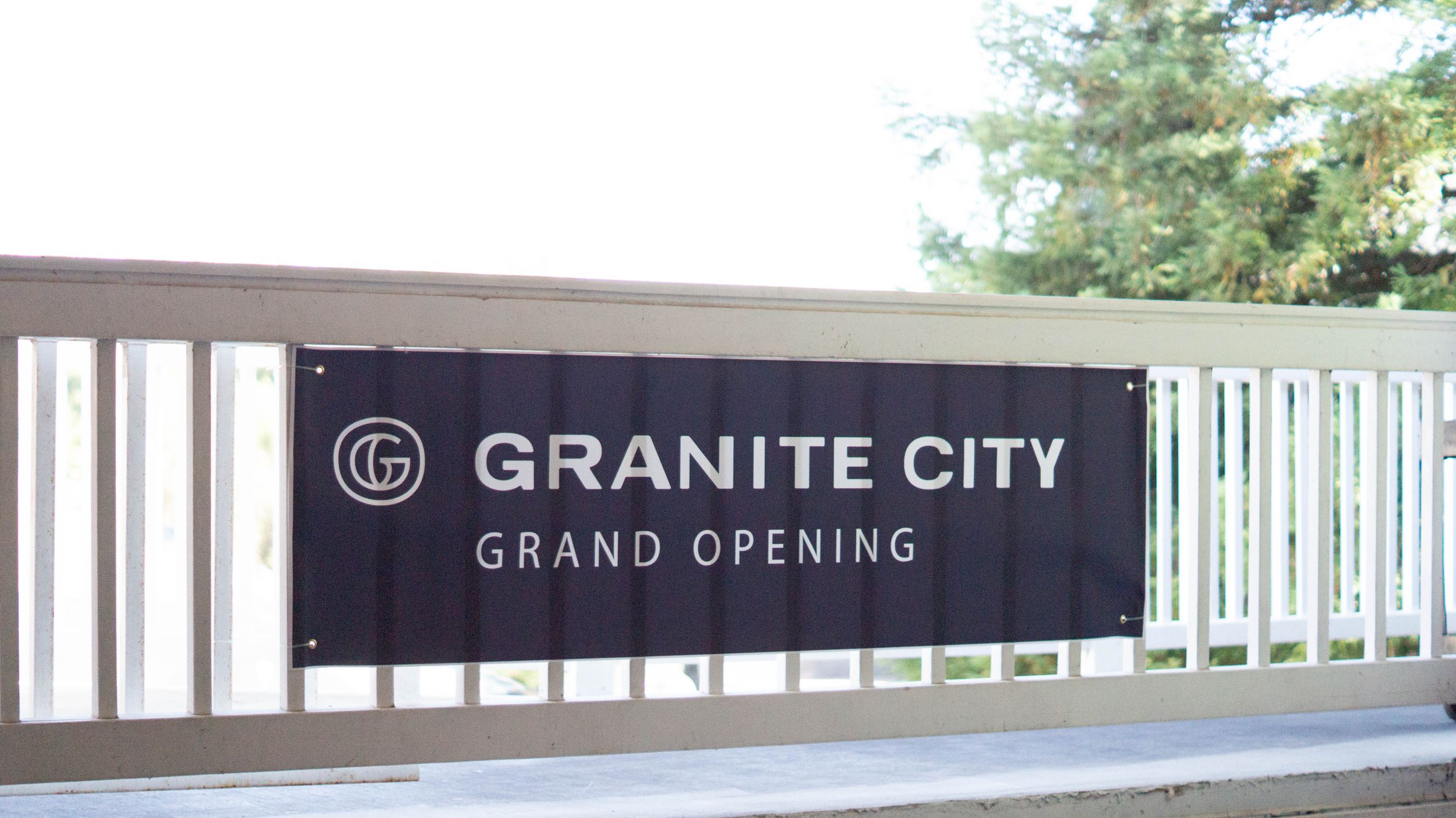 Black and white Granite City grand opening banner displayed on modern architectural facade.
