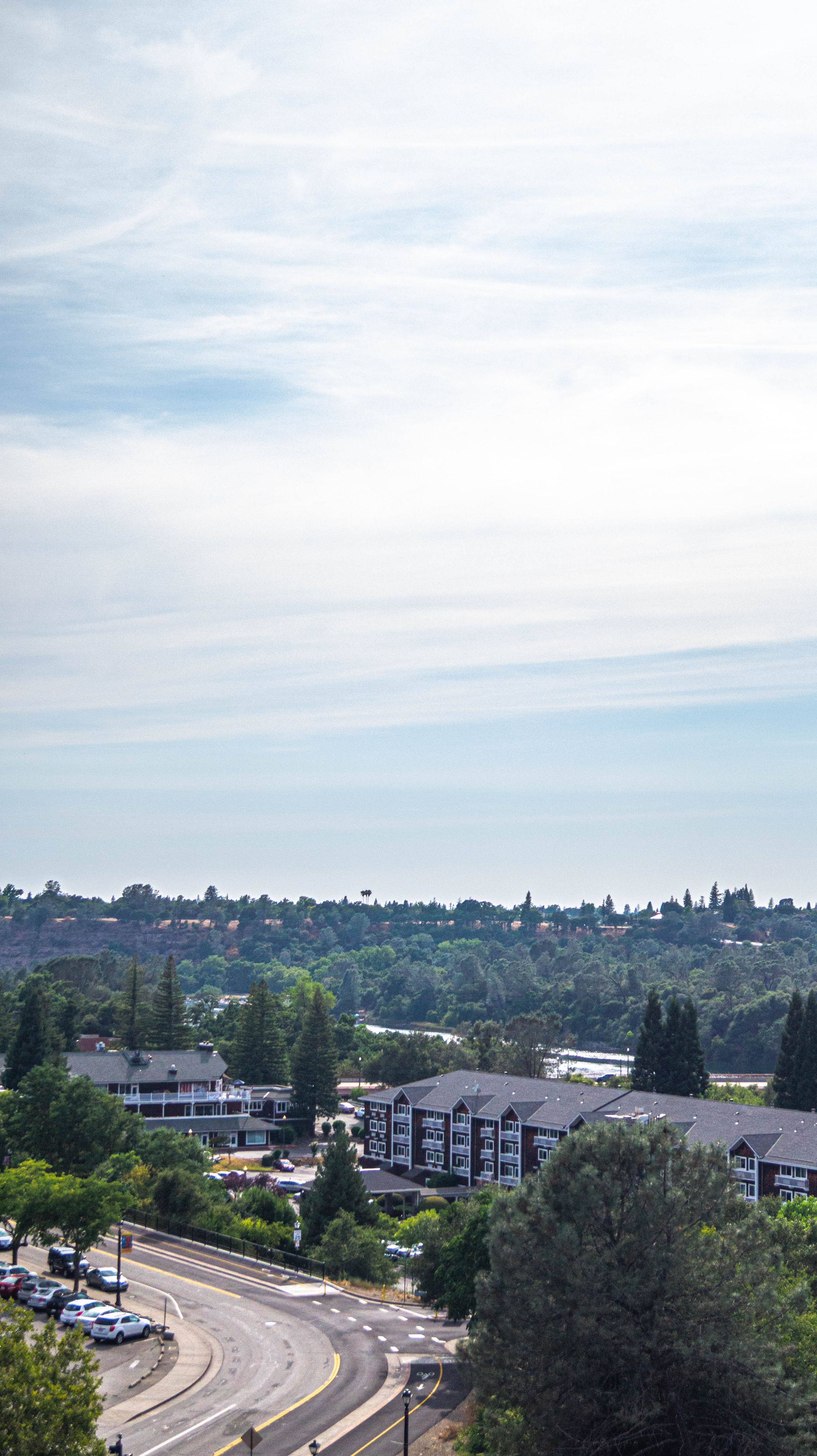 Aerial view of a suburban neighborhood with winding roads and apartment buildings under blue sky.