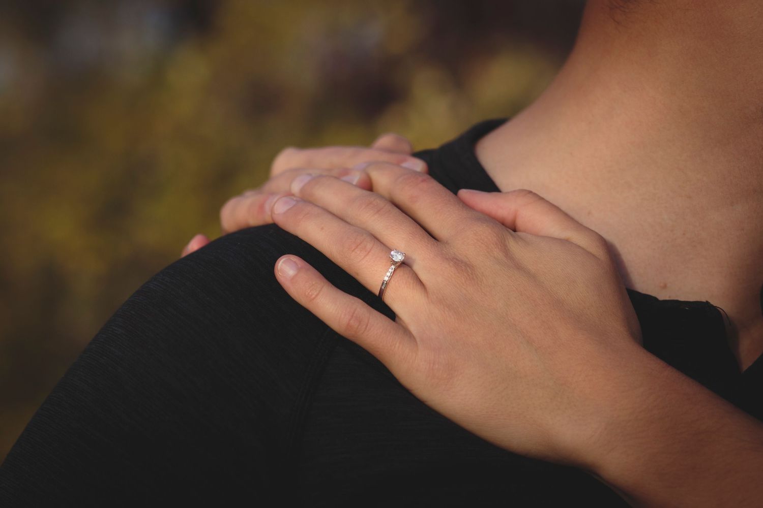 Engagement photo with brides hands on grooms shoulder showing the engagement ring.