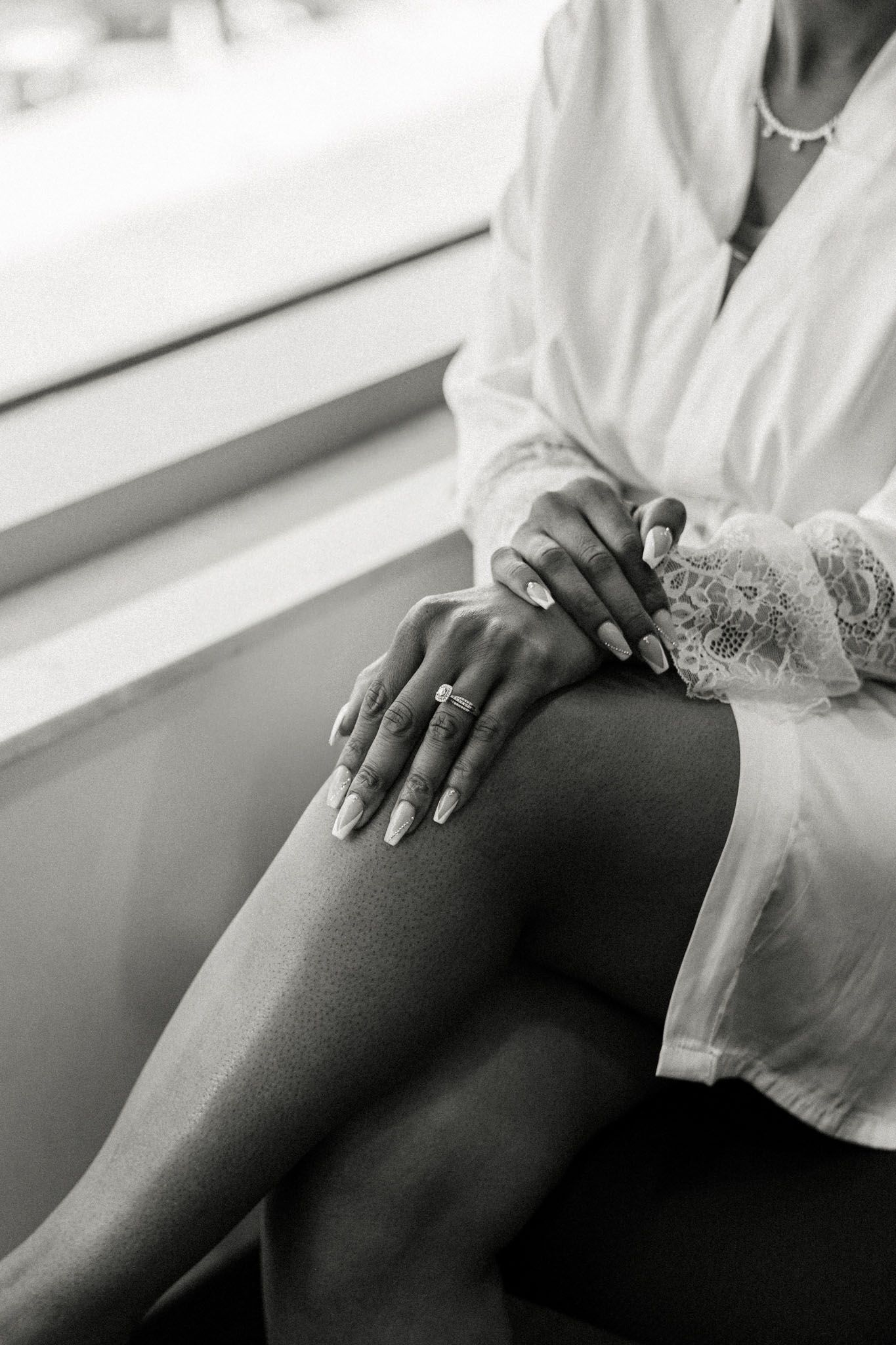 Bride on her wedding day showing off her ring while wearing her bridal robe.