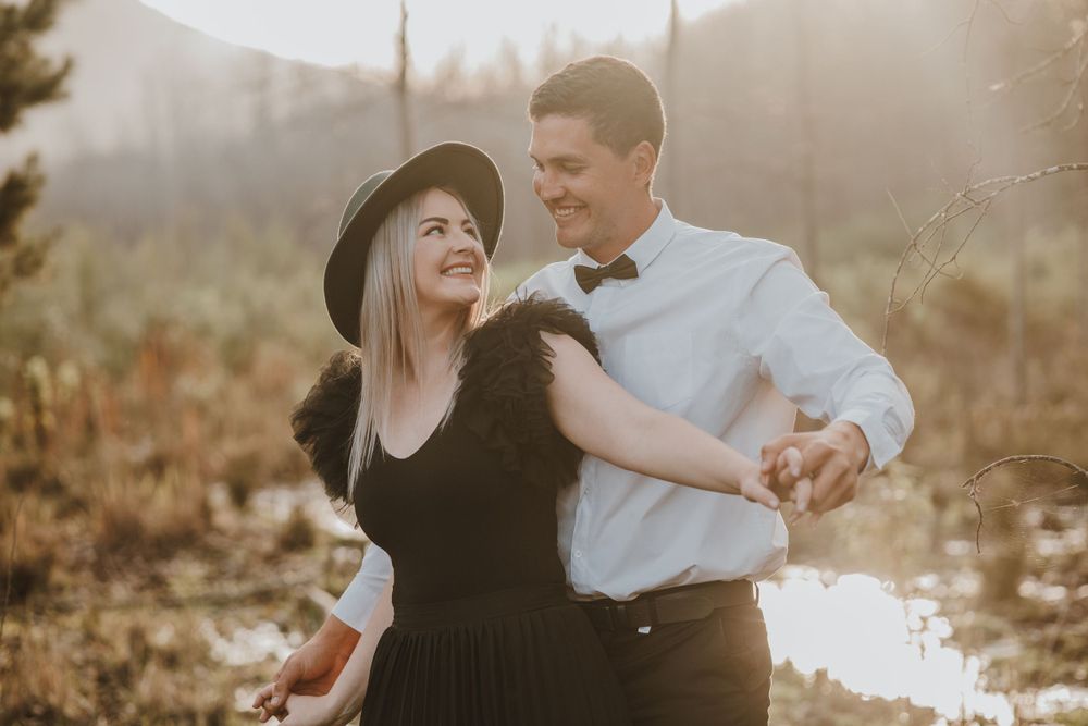 Dancing couple in formal wear against mountain landscape at golden hour.