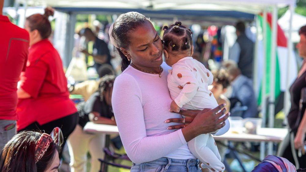 Family members sharing a tender moment at an outdoor community festival.