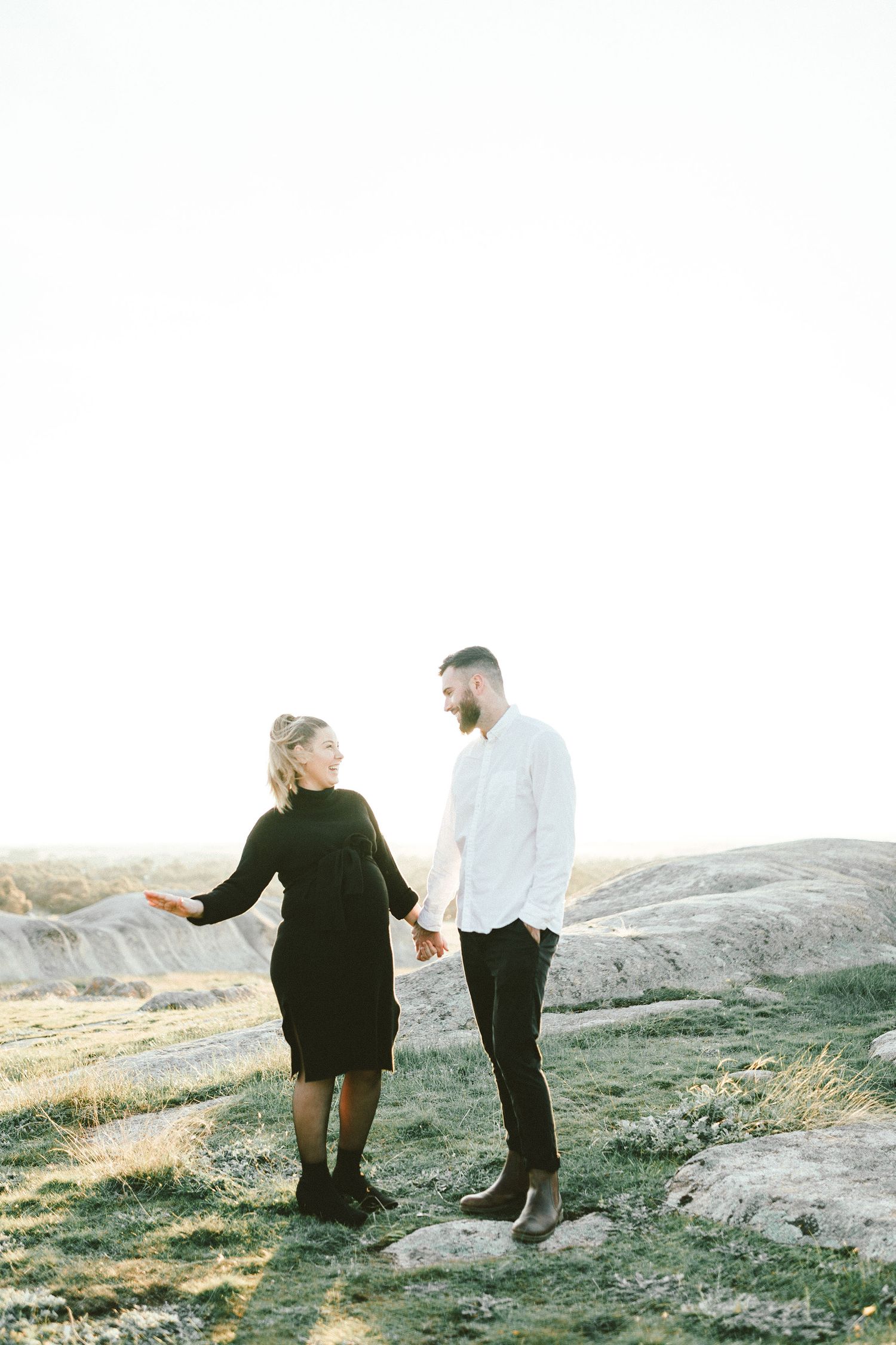 A couple enjoys a moment together on rocky terrain during golden hour.
