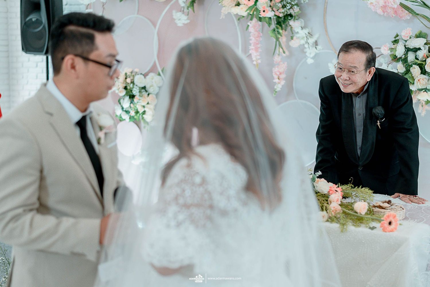 Wedding ceremony with pink and white floral backdrop and decorative elements.