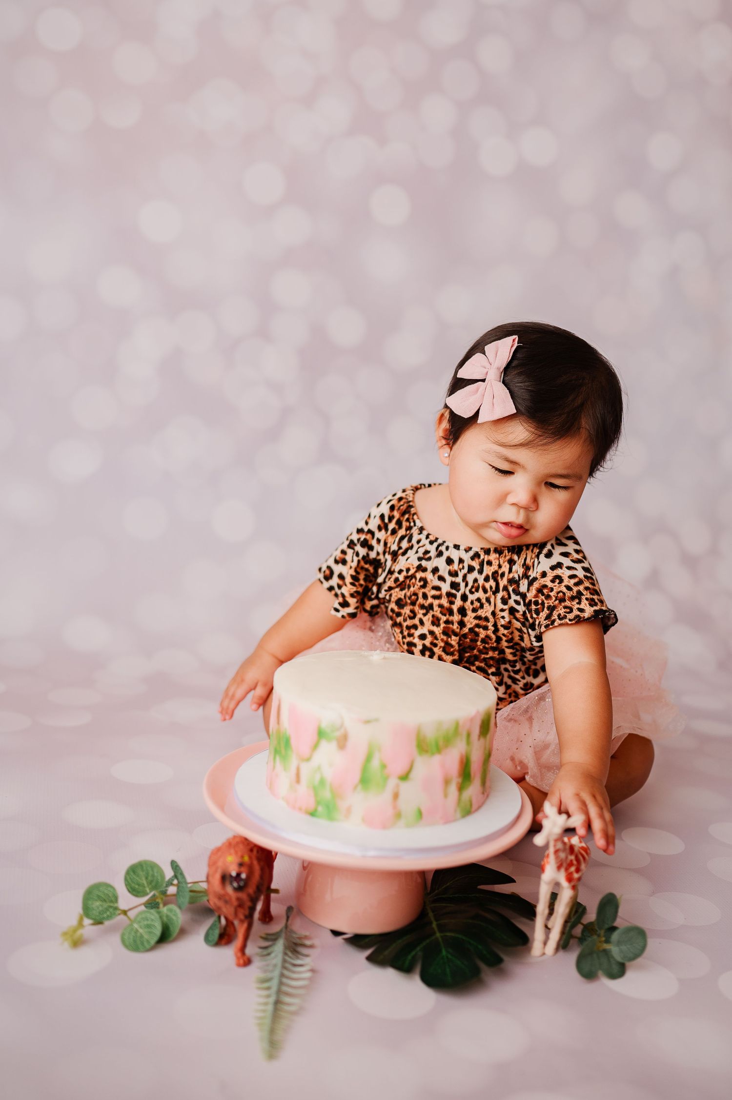 one year old looking at decorations next to cake smash cake