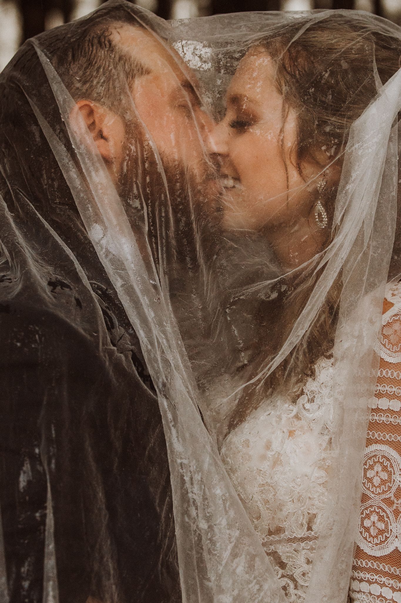 Intimate wedding portrait through delicate veil creating romantic soft focus effect.
