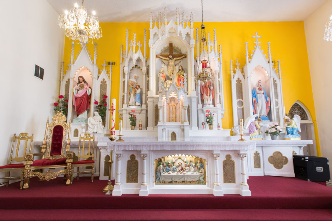 Ornate white Catholic church altar with religious statues and gothic architectural details.