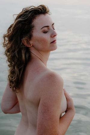 Intimate portrait against serene ocean background during golden hour.
