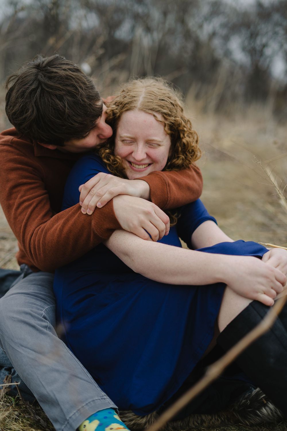jake hugging emily and kissing her cheeks - couple photography in madison wisconsin