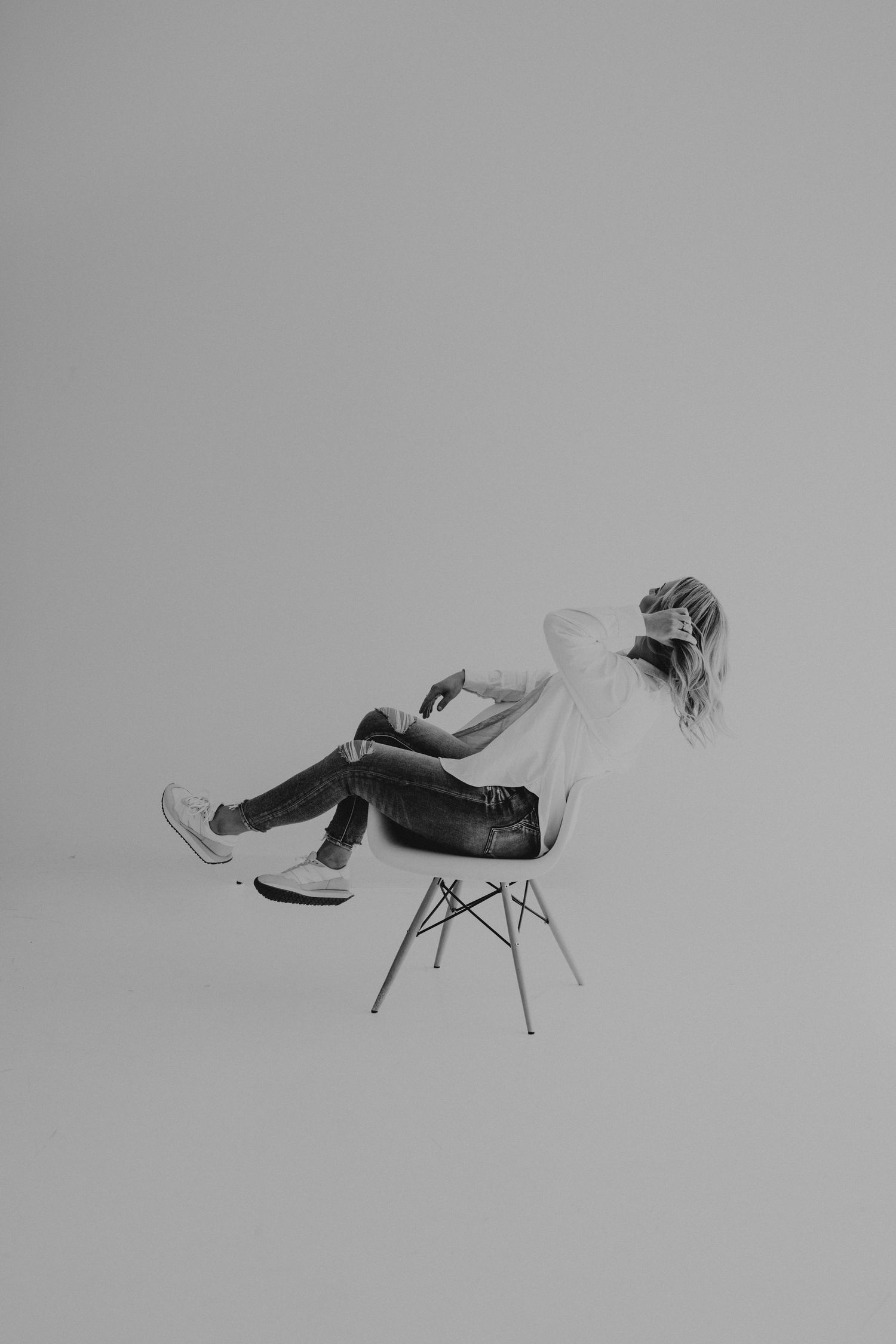 An artistic black and white portrait of someone reclining in a modern chair.