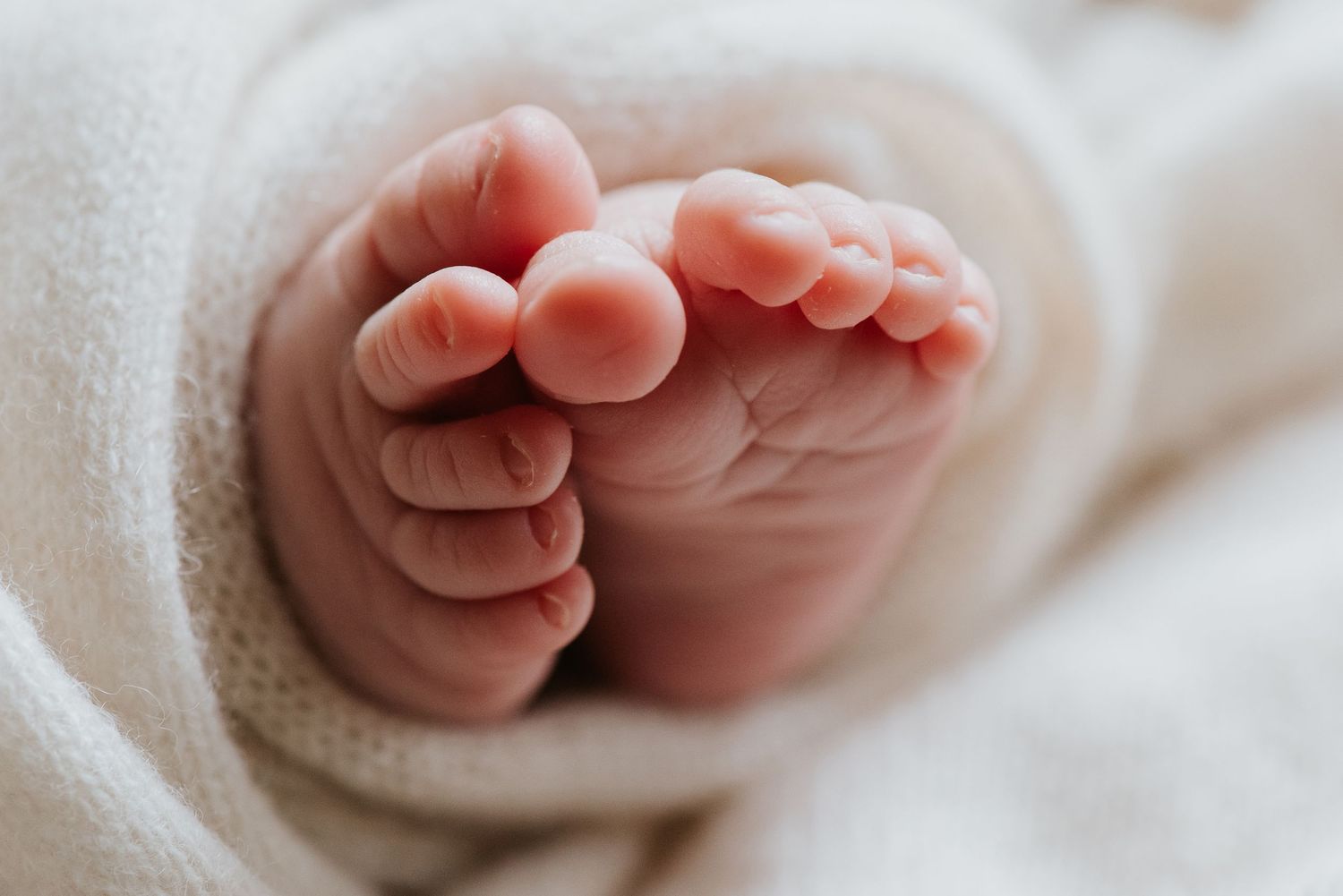 Close-up of newborn toes wrapped in Cream blanket