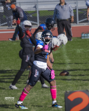 Football player in blue uniform with pink accessories gestures during game play.