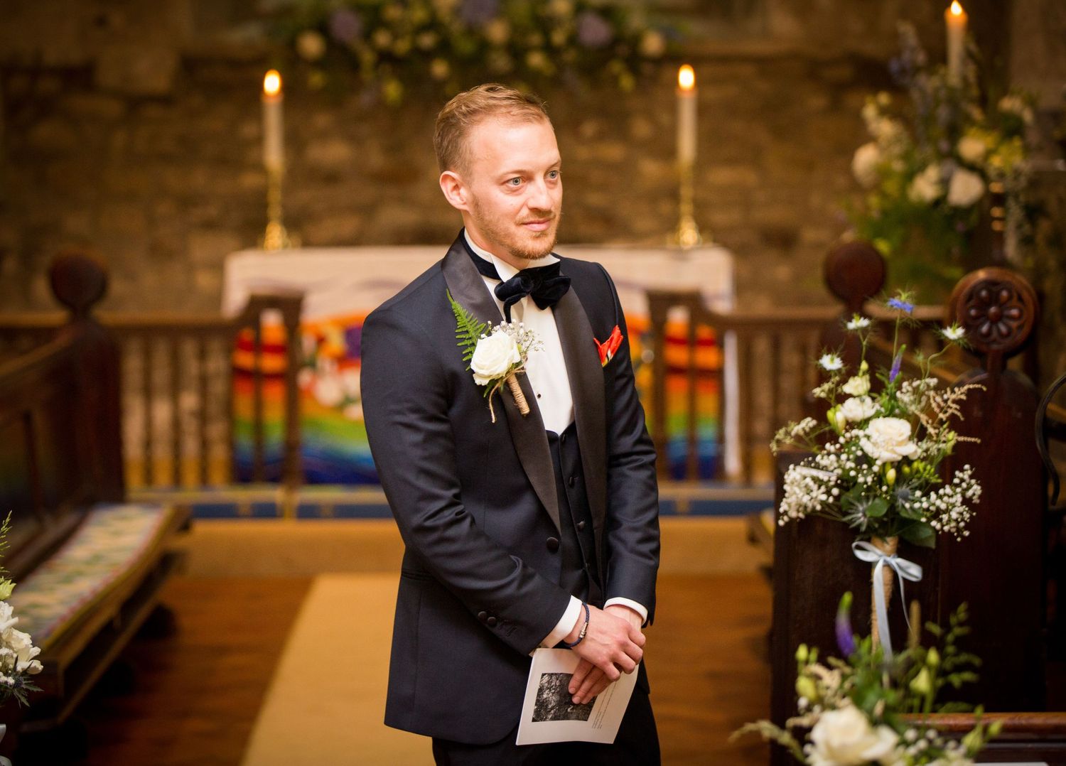 Emotional moment during wedding ceremony in stone church with candlelight.