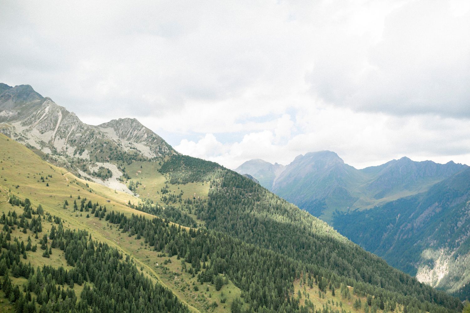 Majestic mountain landscape with forested slopes under cloudy skies.