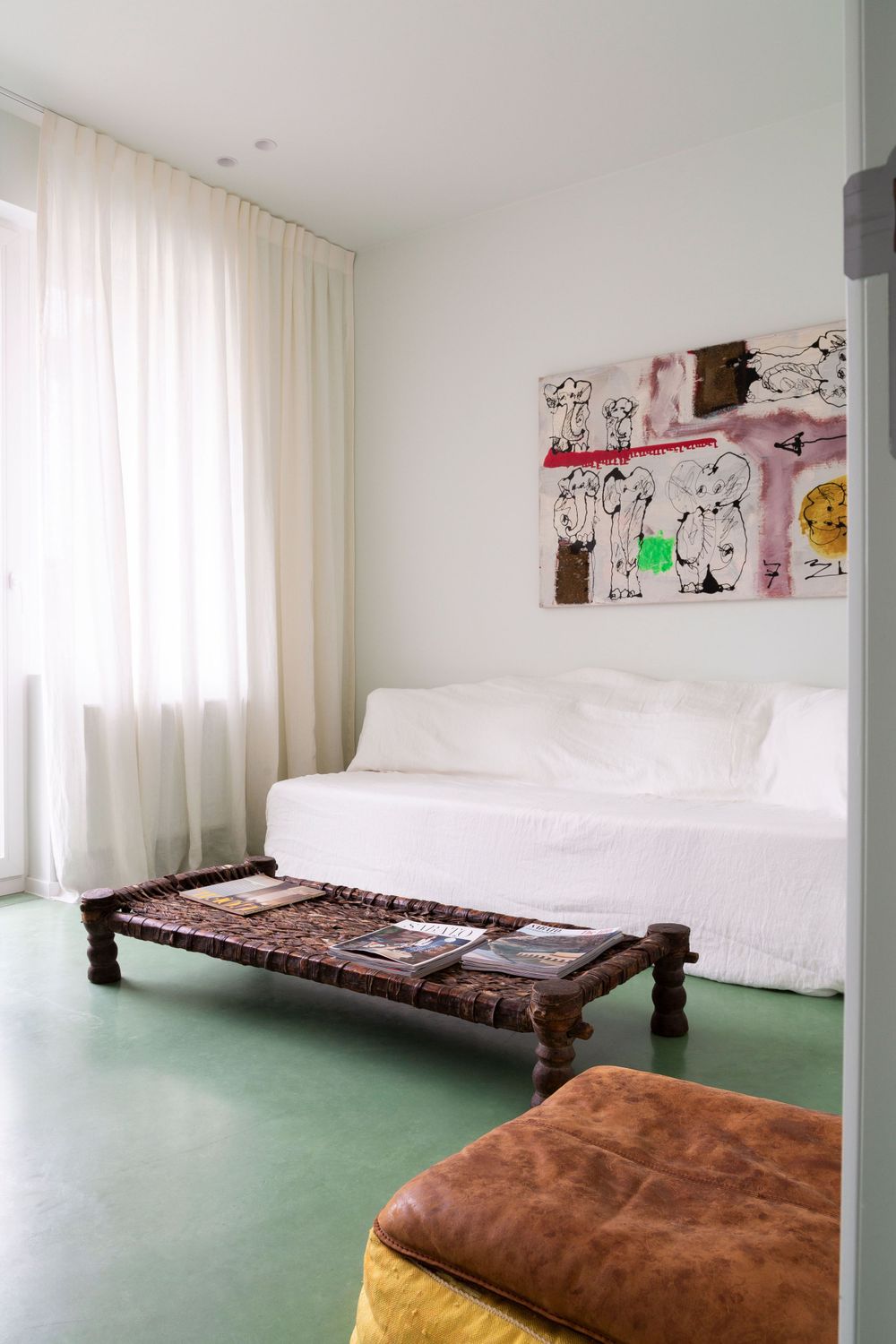 Contemporary bedroom with white bedding, artwork, and mint green flooring.