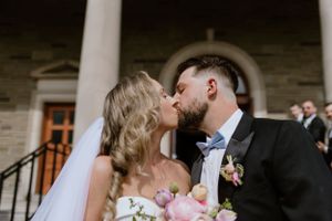 Bride and groom kissing in front of St. Thomas Aquinas Church after ceremony in Halifax Nova Scotia